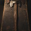 Hand-forged Viking axe with carved Norse warrior handle and etched double blade on rustic wooden bench – custom American bladesmith craftsmanship by Damascus Edges.